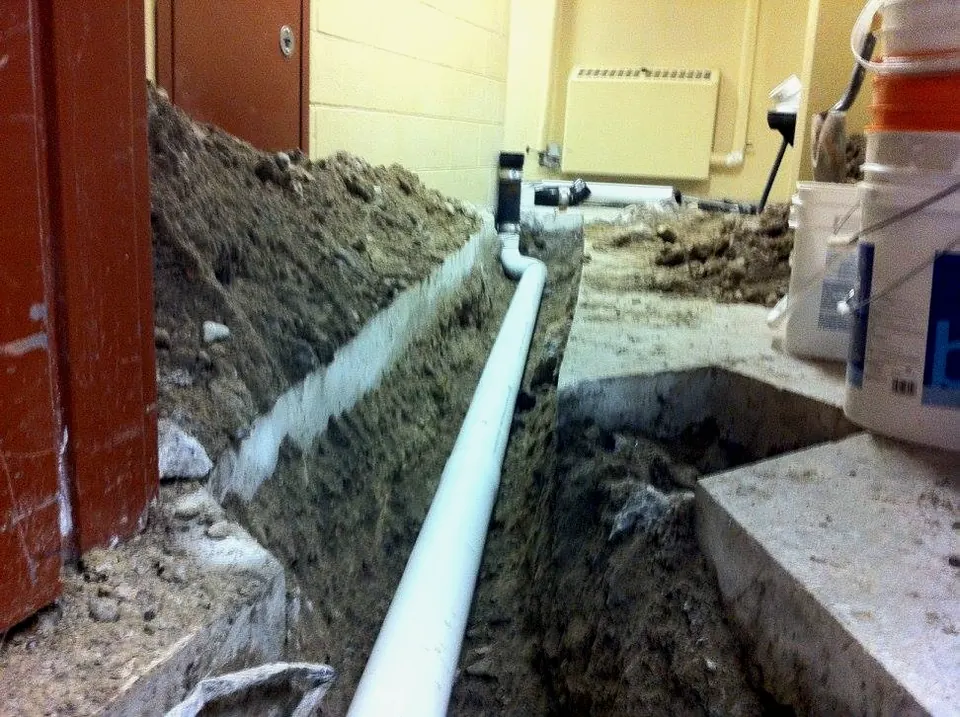 A new drain line laid in a trench beside a house