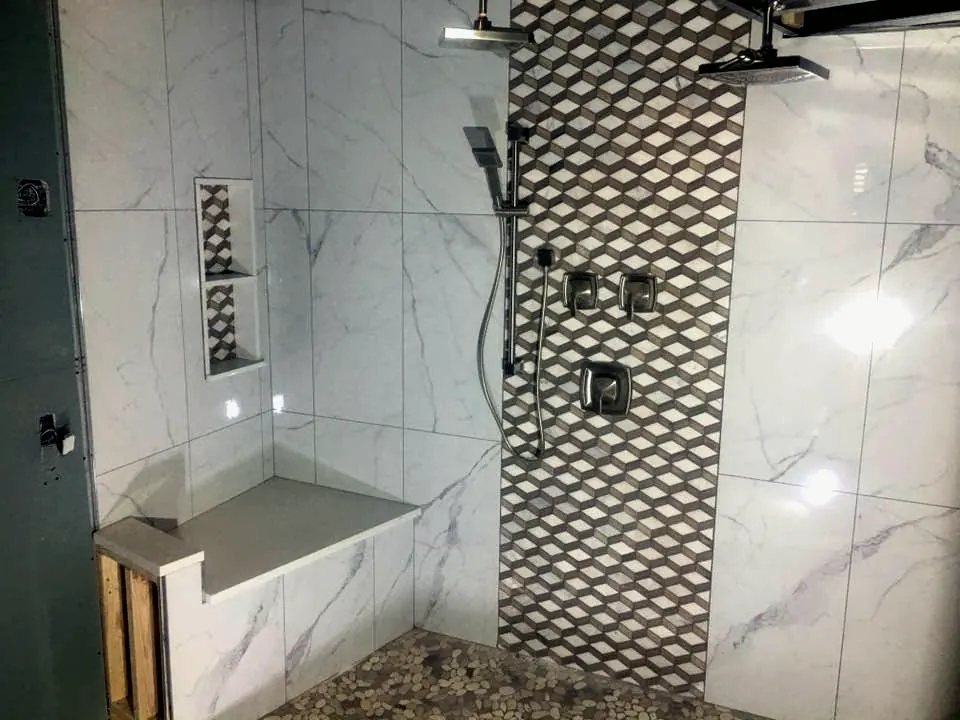 A finished tiled walk-in shower with a bench and niche
