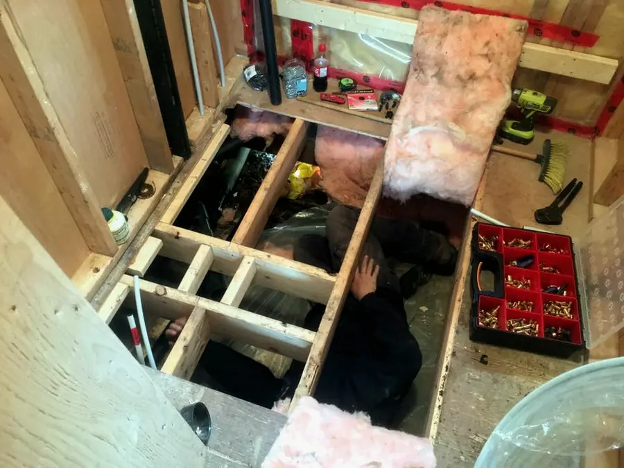 Plumbing work through an opened floor into a crawlspace